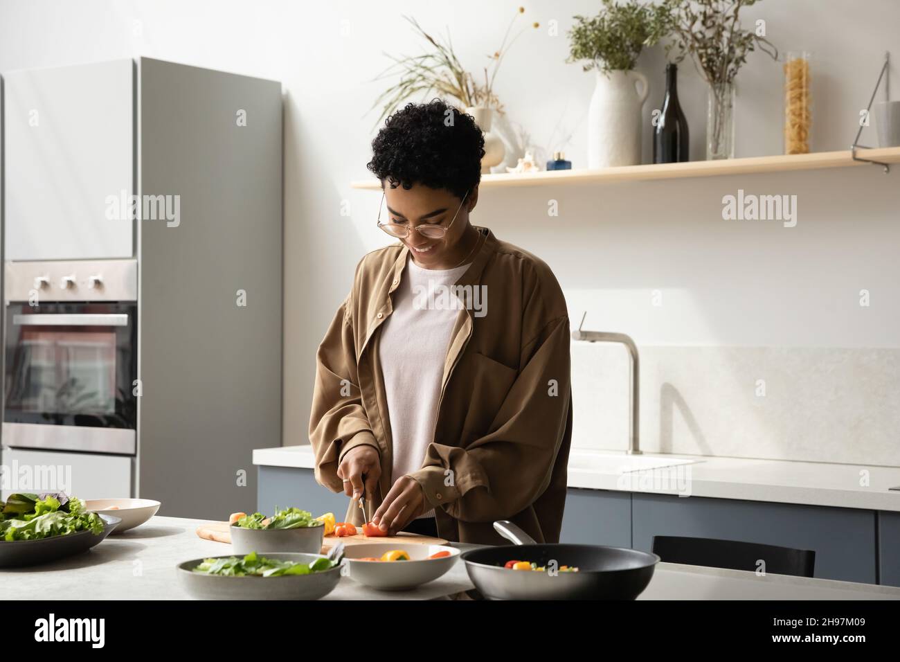 Bonne jeune femme afro-américaine préparant des aliments dans la cuisine. Banque D'Images