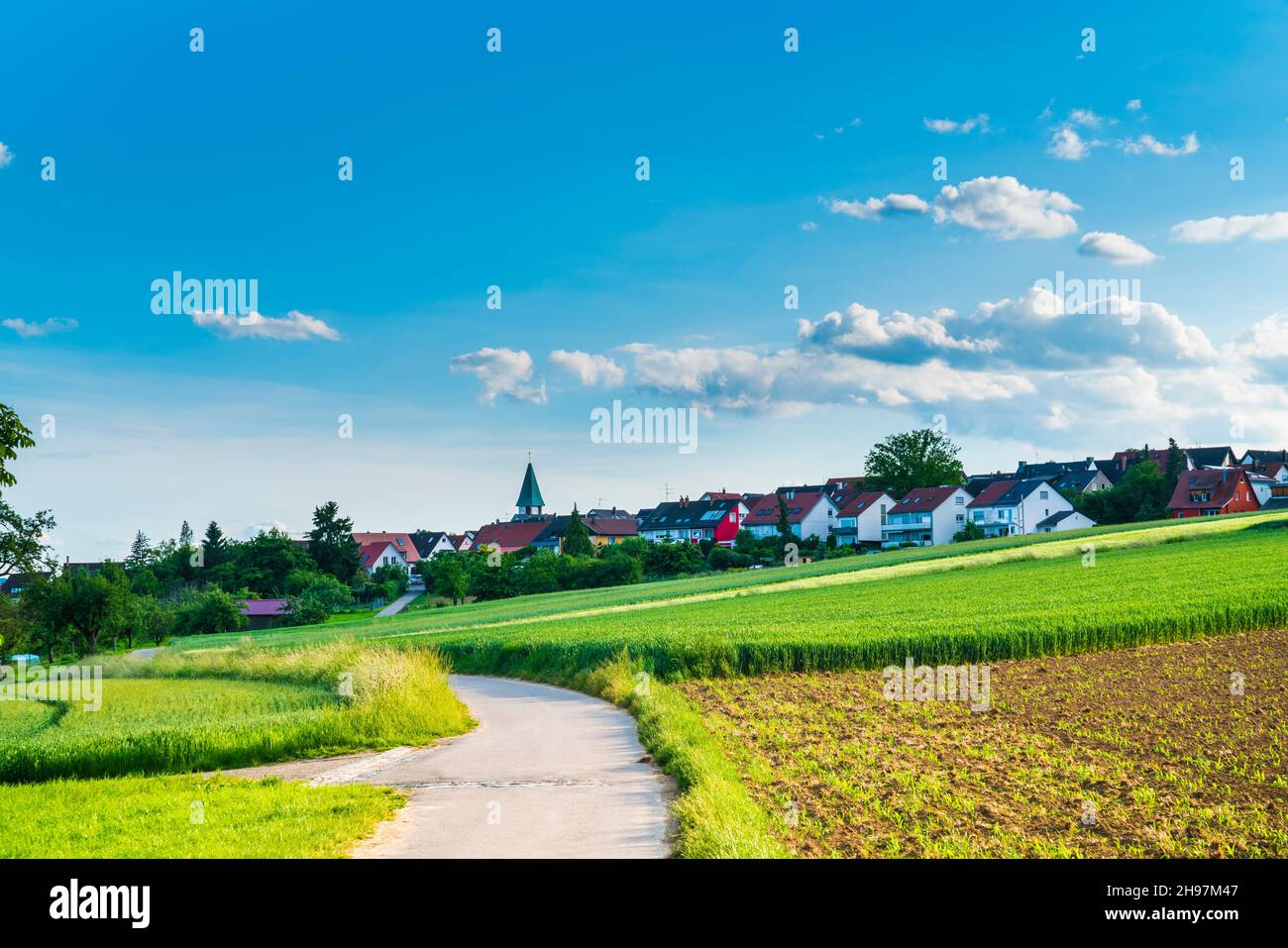 Allemagne, ville ostfildern kemnat maisons et église de derrière la route courbe et les champs verts en été une belle vue nature paysage avec le soleil Banque D'Images