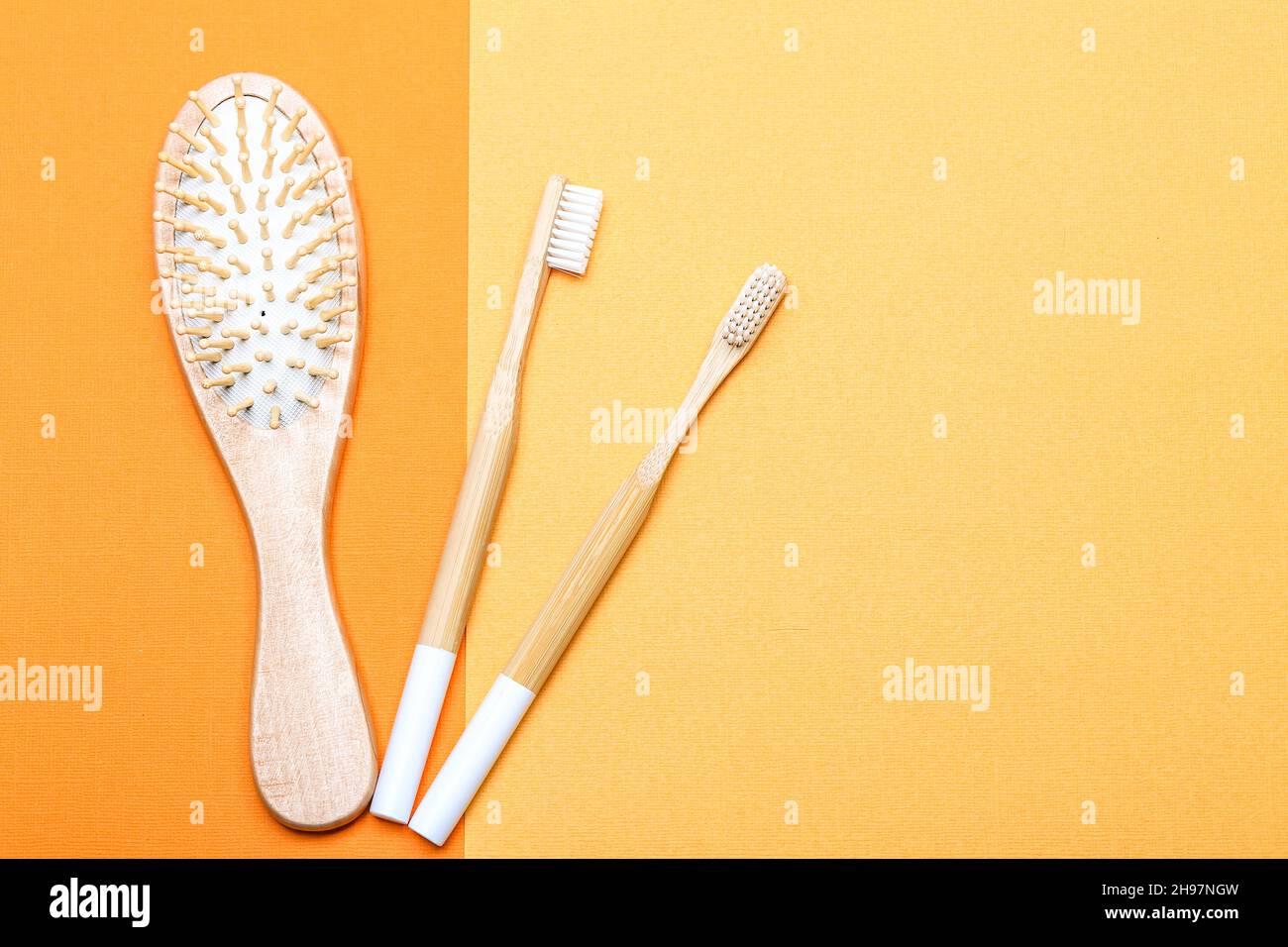 concept zéro déchet avec accessoires de salle de bains sur fond de papier jaune. brosse à cheveux en bois et deux brosses à dents en bambou Banque D'Images