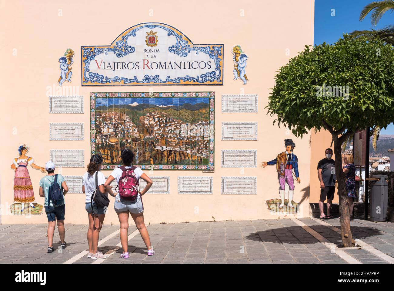 RONDA, ESPAGNE - 8 AOÛT 2021 : vue arrière des jeunes touristes devant un mur avec photo de Ronda Banque D'Images