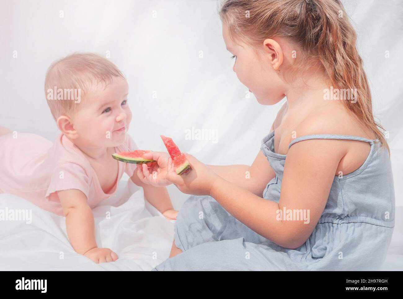 Les enfants mangent de la pastèque.La grande sœur traite bébé avec de la pastèque Banque D'Images
