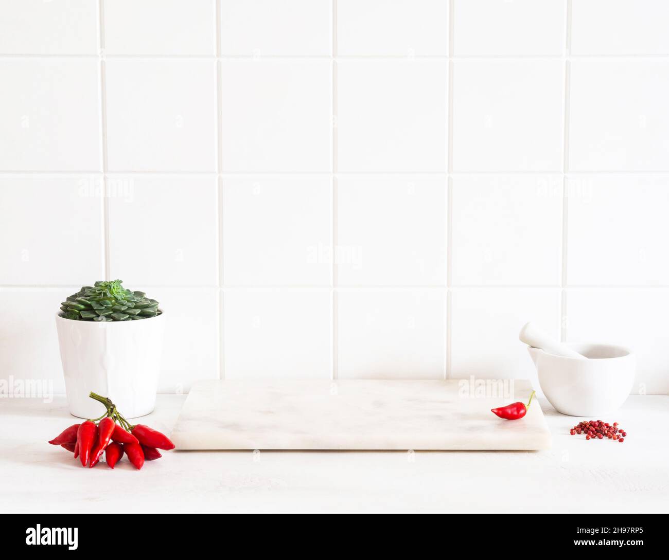 Comptoir de cuisine blanc avec carreaux blancs, plateau en marbre pour la présentation des produits ou la publicité.Épices et ustensiles de cuisine des deux côtés.Vue avant Banque D'Images