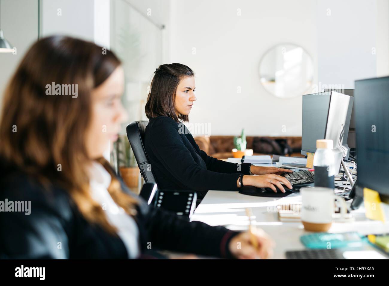 Femme assise sur un bureau et travaillant avec un ordinateur dans un bureau Banque D'Images