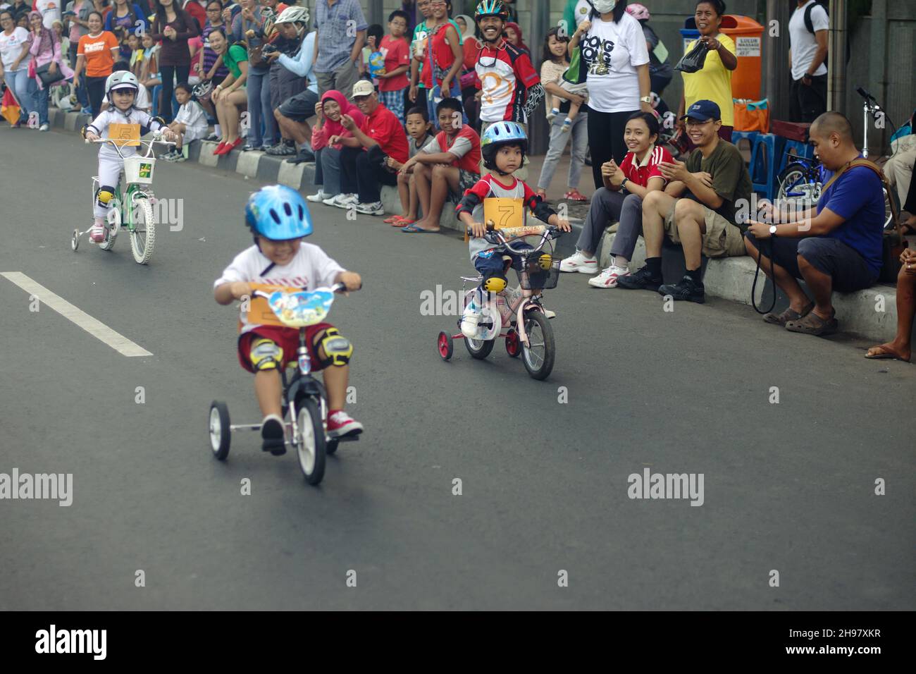 Course cycliste pour enfants en mouvement rapide dans la rue pendant la journée sans voiture, le week-end du matin avec une foule de personnes regardant en arrière-plan.Mise au point sélective. Banque D'Images