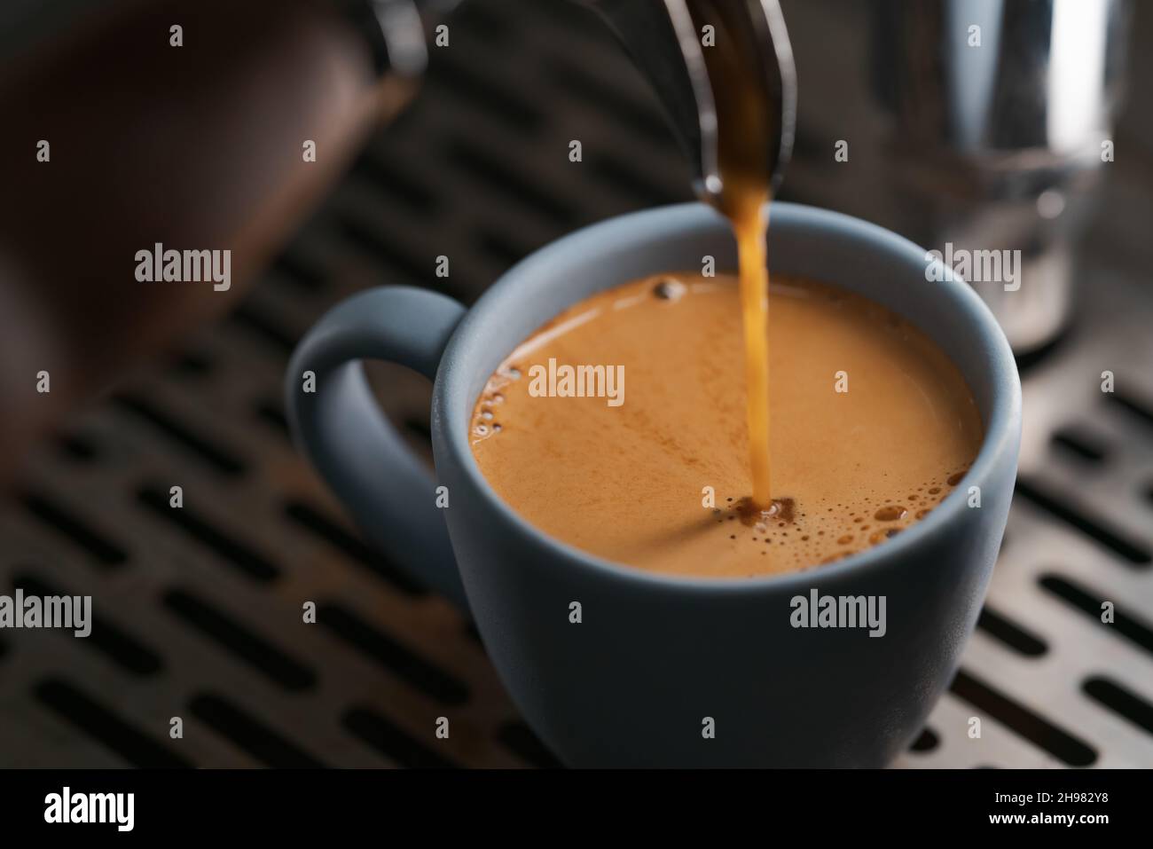 Gros plan espresso verser avec un porte-filtre à bec unique dans une tasse bleue, peu de profondeur de mise au point Banque D'Images