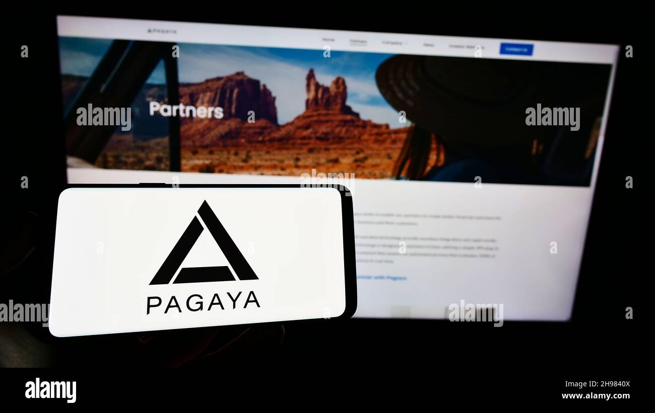 Personne tenant le téléphone portable avec le logo de la société de technologie financière Pagaya Investments sur l'écran en face de la page Web d'affaires.Mise au point sur l'affichage du téléphone. Banque D'Images