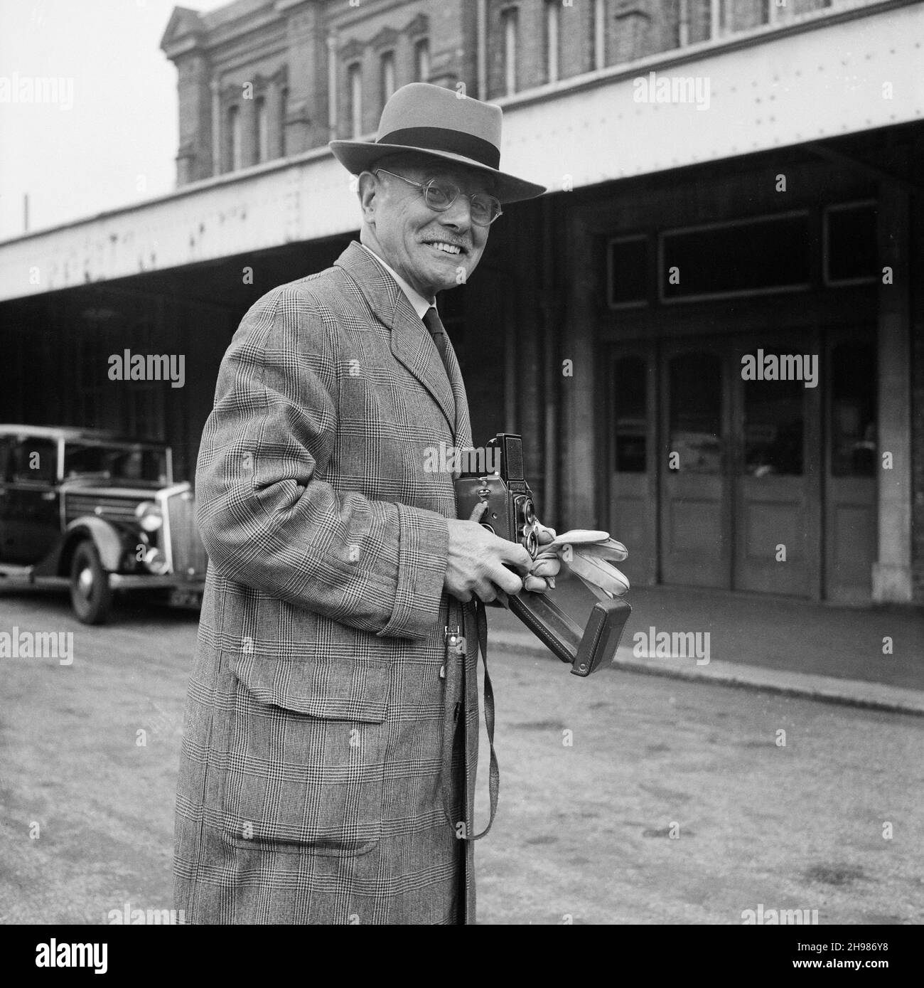 John Laing tenant une caméra Rolleiflex à l'extérieur de la gare de Bournemouth, 30/05/1953.Un portrait de John Laing tenant une caméra Rolleiflex devant la gare de Bournemouth, lors d'une sortie du bureau de Laing à Londres jusqu'à Bournemouth. Banque D'Images