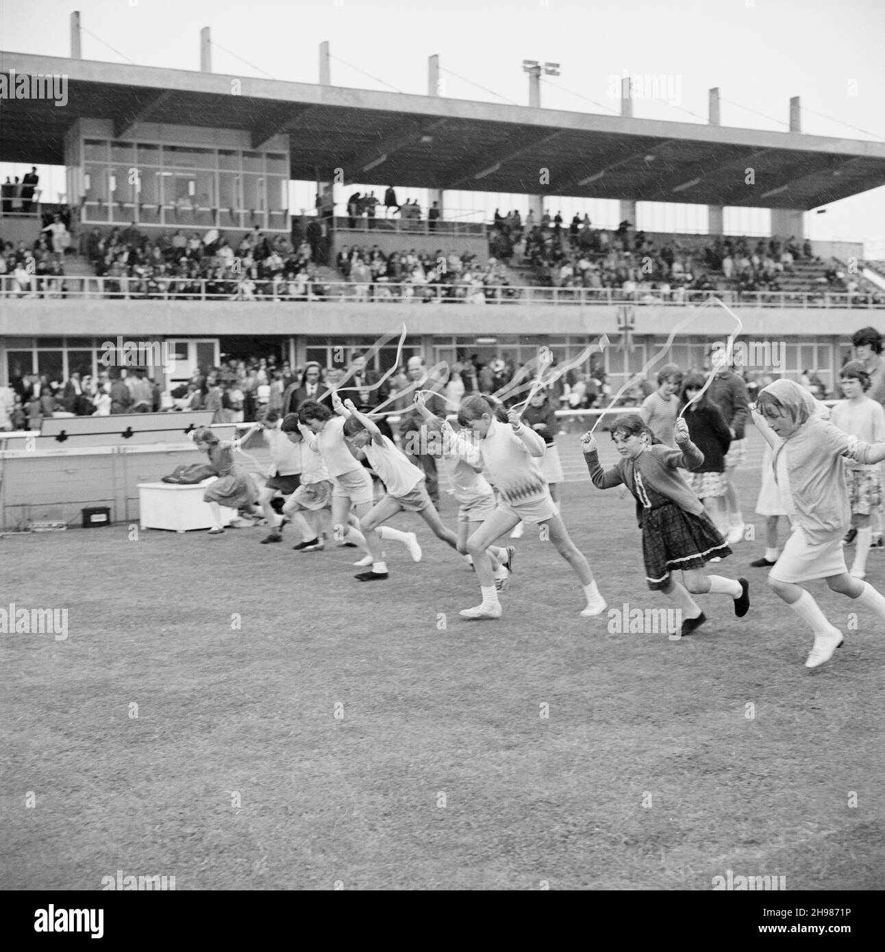 Stade Copthall, Hendon, Barnett, Londres, 25/06/1966.Les filles quittent la ligne de départ d'une course à sauter, avec des spectateurs dans un stand au-delà, lors de la Journée annuelle des sports de Laing qui s'est tenue au stade Copthall.En 1966, la Journée annuelle des sports des employés de Laing a eu lieu le 25 juin au stade Copthall à Hendon.C'était la première fois que l'événement s'y tenait, ayant eu lieu auparavant le terrain de sport de Laing à Elstree.Parmi les différents événements, on compte l'athlétisme et une compétition de football, et les concurrents ont voyagé depuis les bureaux et sites régionaux de la société, notamment en Écosse et en Carlisle.Il y en avait Banque D'Images