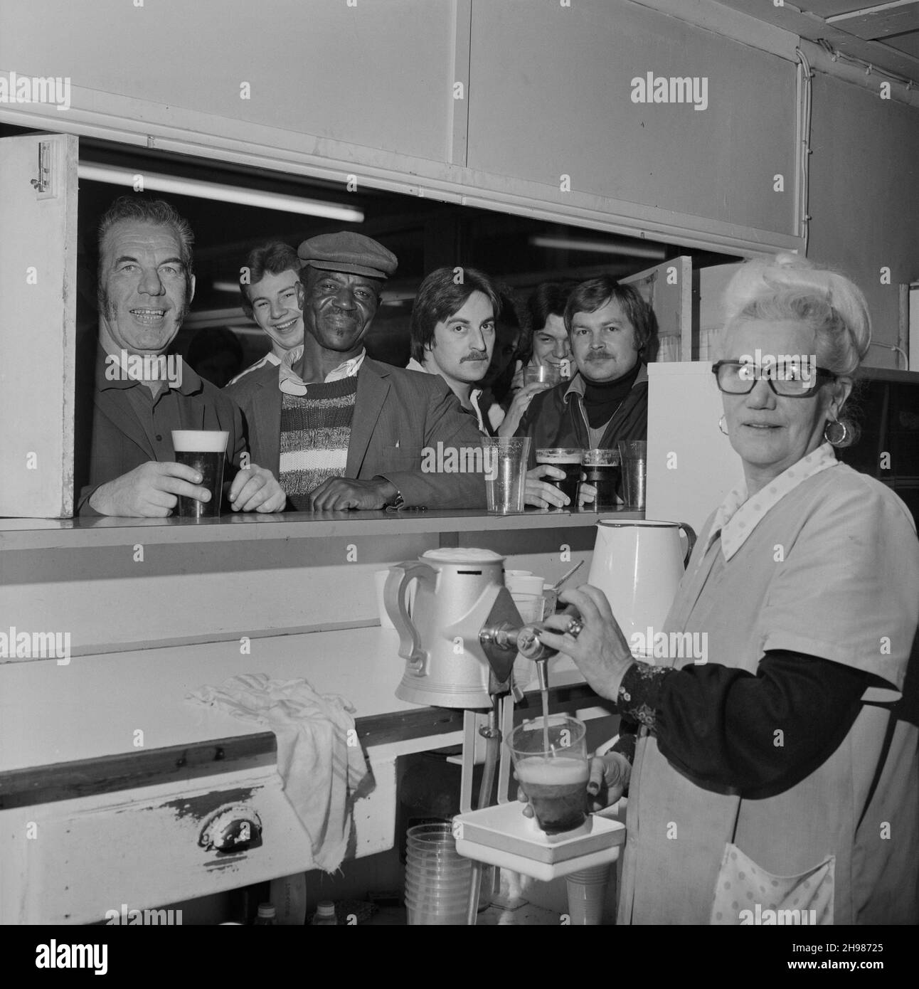 Dixon House, 75 Fenchurch Street, Londres, 01/11/1978.Une femme servant de la bière à des hommes debout à une trappe de service lors d'une fête de remerciement tenue dans la cantine du site à Dixon House.Cette fête de remerciement a été organisée par la région de Londres de Laing pour son personnel qui travaillait à la reconstruction de l'intérieur de la Dixon House. Banque D'Images