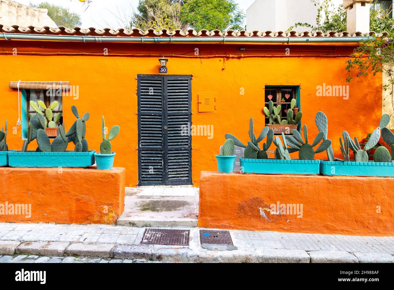 Extérieur d'une maison orange animée avec des plantes cactus en pot sur Carrer del Polvorí, El Terreno, Palma, Majorque, Espagne Banque D'Images