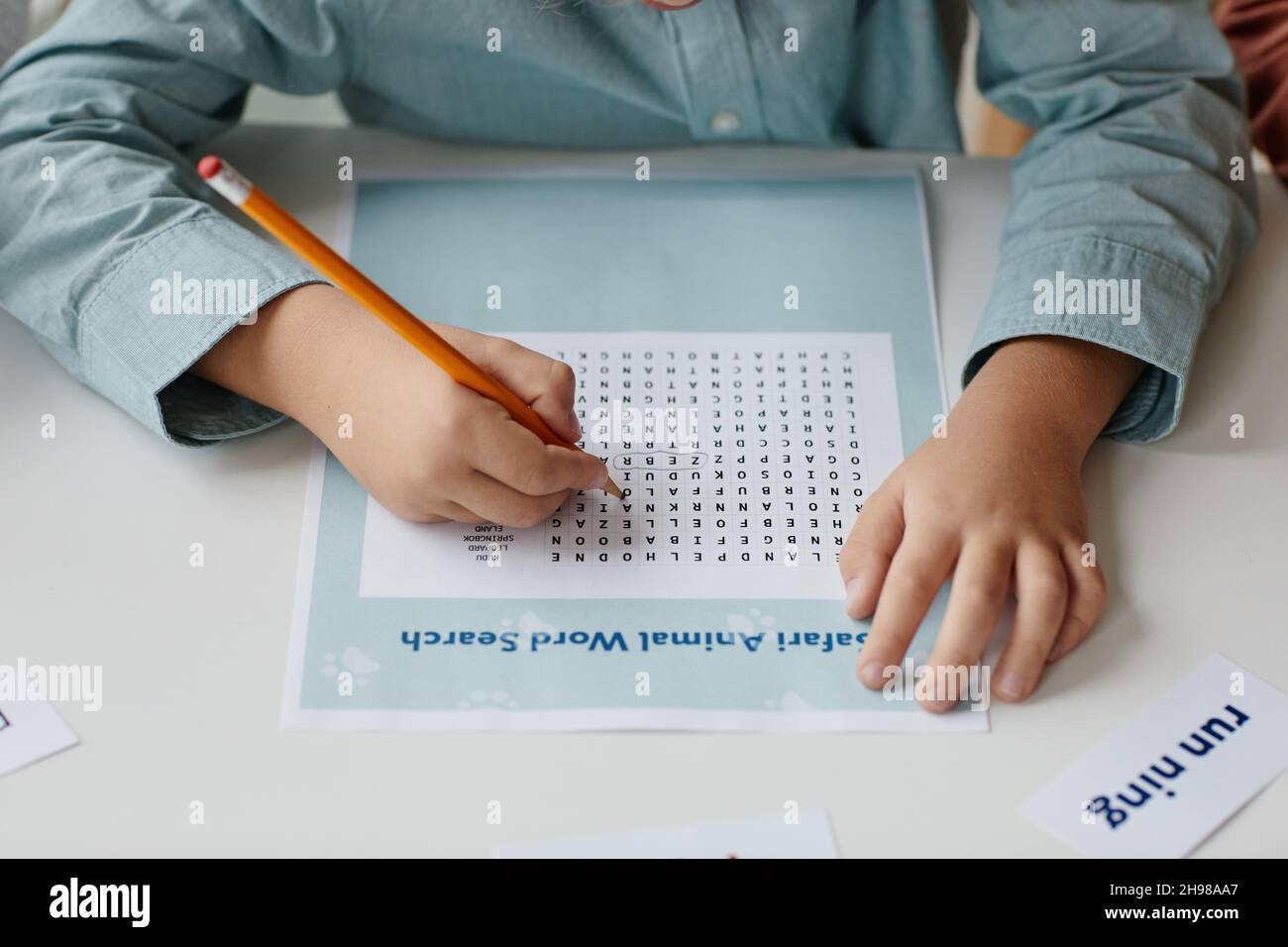 Gros plan d'un élève qui prend des notes avec un crayon tout en se préparant à ses devoirs à la table Banque D'Images