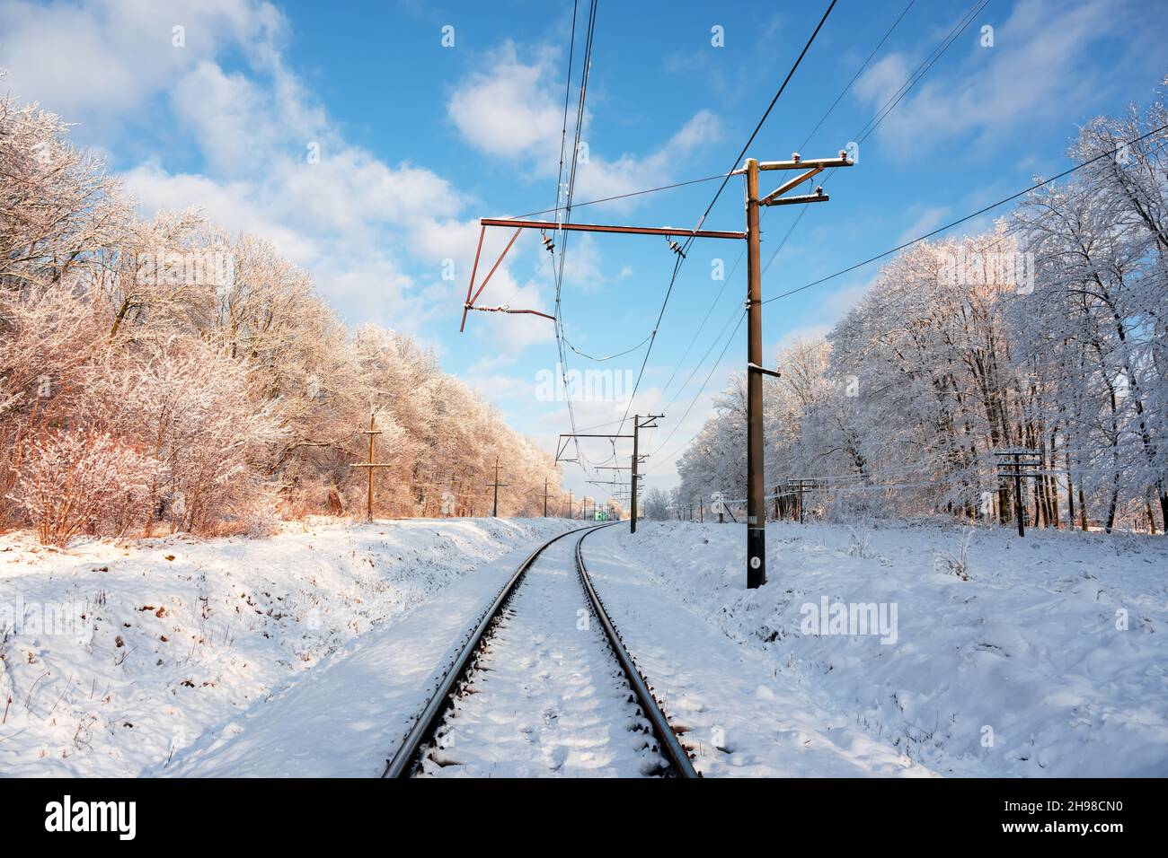 Chemin de fer vide avec ligne électrique principale dans la forêt d'hiver.Scène enneigée sur un coucher de soleil avec chemin de fer Banque D'Images