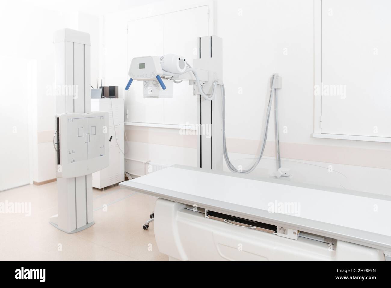 Service de radiologie dans un hôpital moderne.Salle de radiologie avec scanner et lit vide.Le technicien règle un appareil à rayons X.Examen du thorax, du cœur Banque D'Images