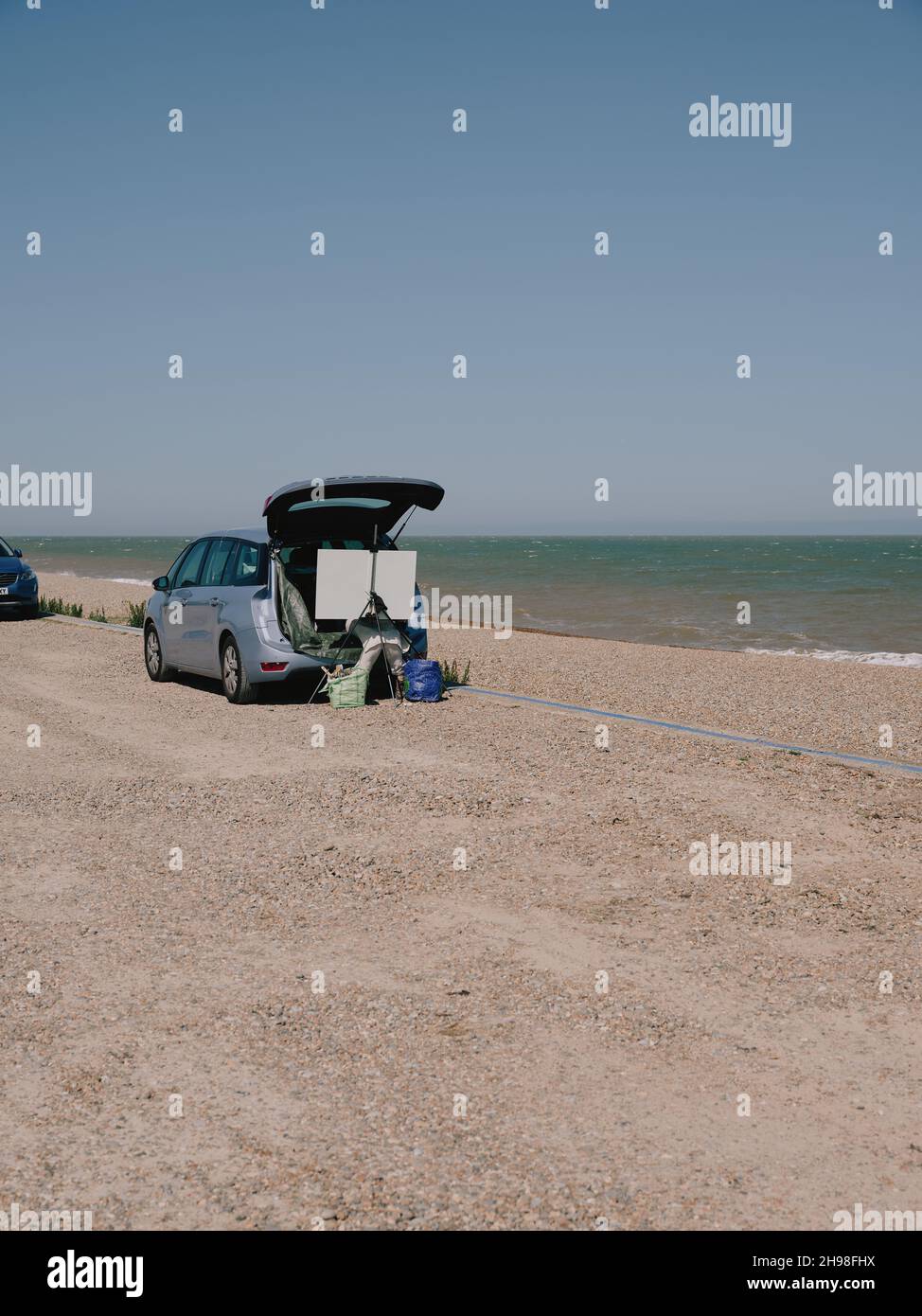 Un artiste peint depuis le coffre de sa voiture avec un chevalet et une toile sur la côte estivale de la mer du Royaume-Uni - plein air peinture - en plein air Banque D'Images