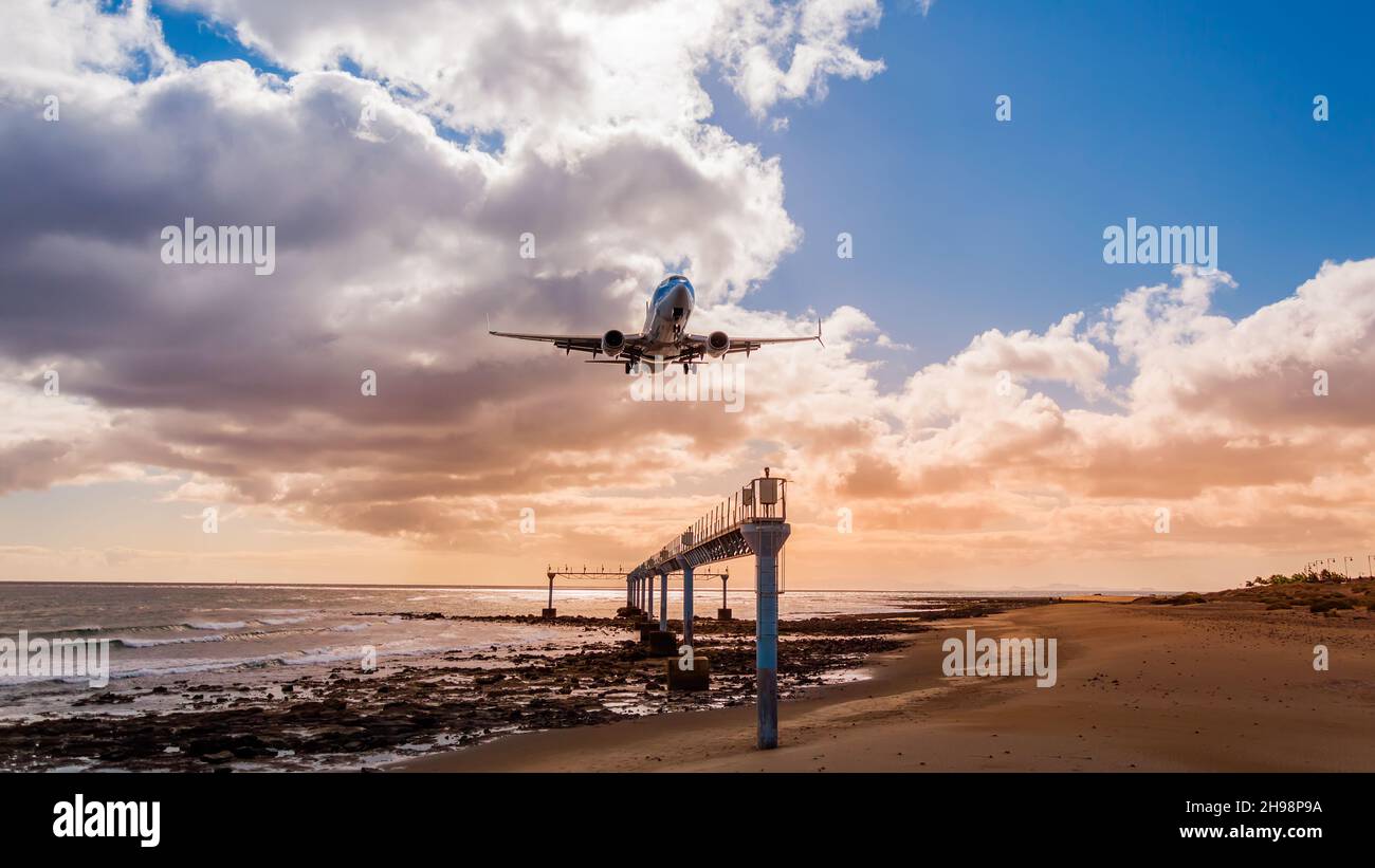 Avion approchant la plage sur l'île de Lanzarote, Espagne.Avion d'atterrissage sur l'océan contre le ciel du coucher du soleil vu du point de vue Mirador de Acercamiento Banque D'Images