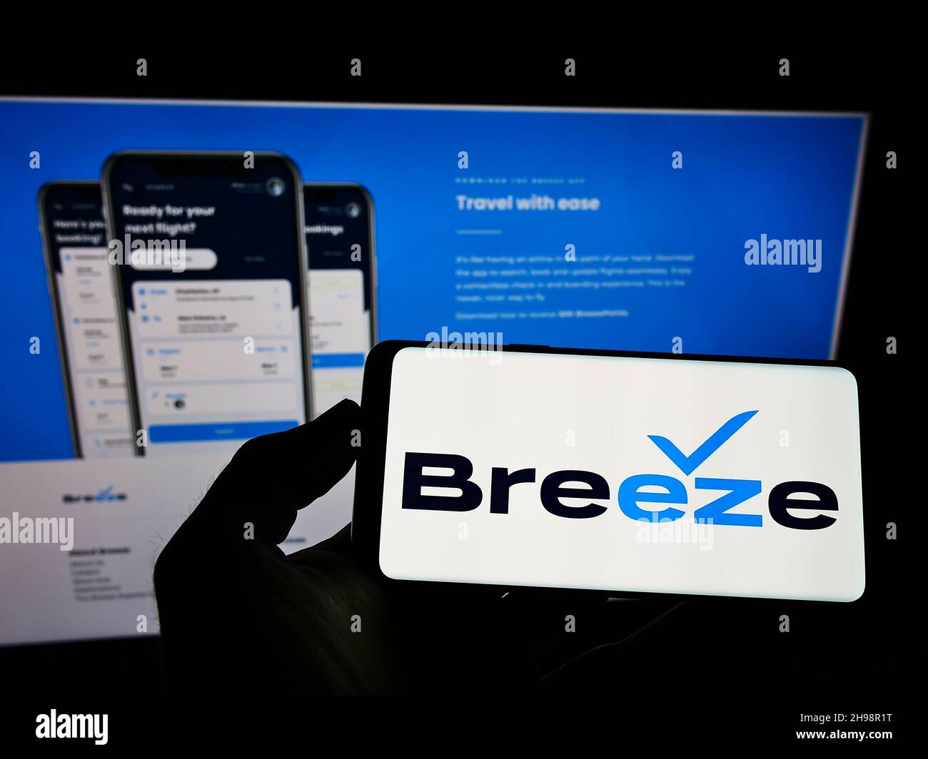 Personne tenant un téléphone portable avec le logo de la compagnie aérienne américaine Breeze Airways à l'écran en face du site Web d'affaires.Mise au point sur l'affichage du téléphone. Banque D'Images