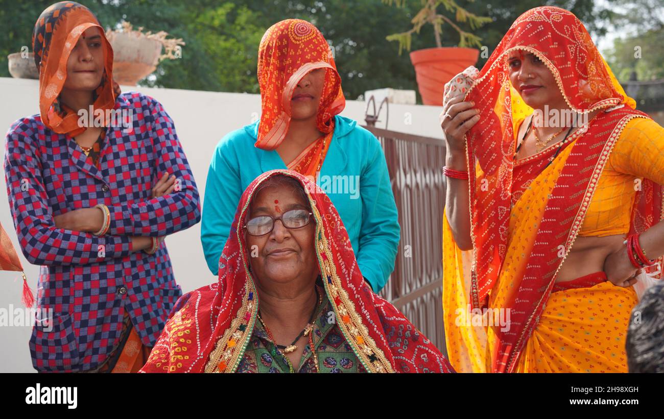 21 novembre 2021 Reengus, Rajasthan, Inde.Femme indienne âgée en robe traditionnelle avec lunettes et chaise avec des membres de la famille. Banque D'Images