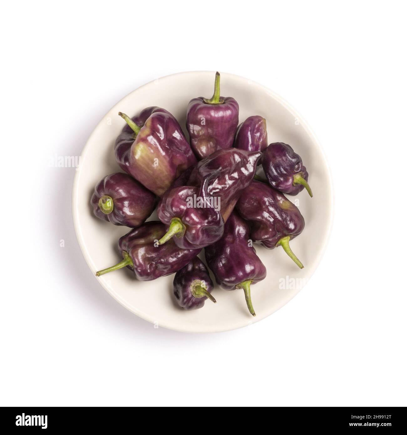poivrons habanero violets sur une assiette, isolés sur fond blanc, vue de dessus en bas Banque D'Images