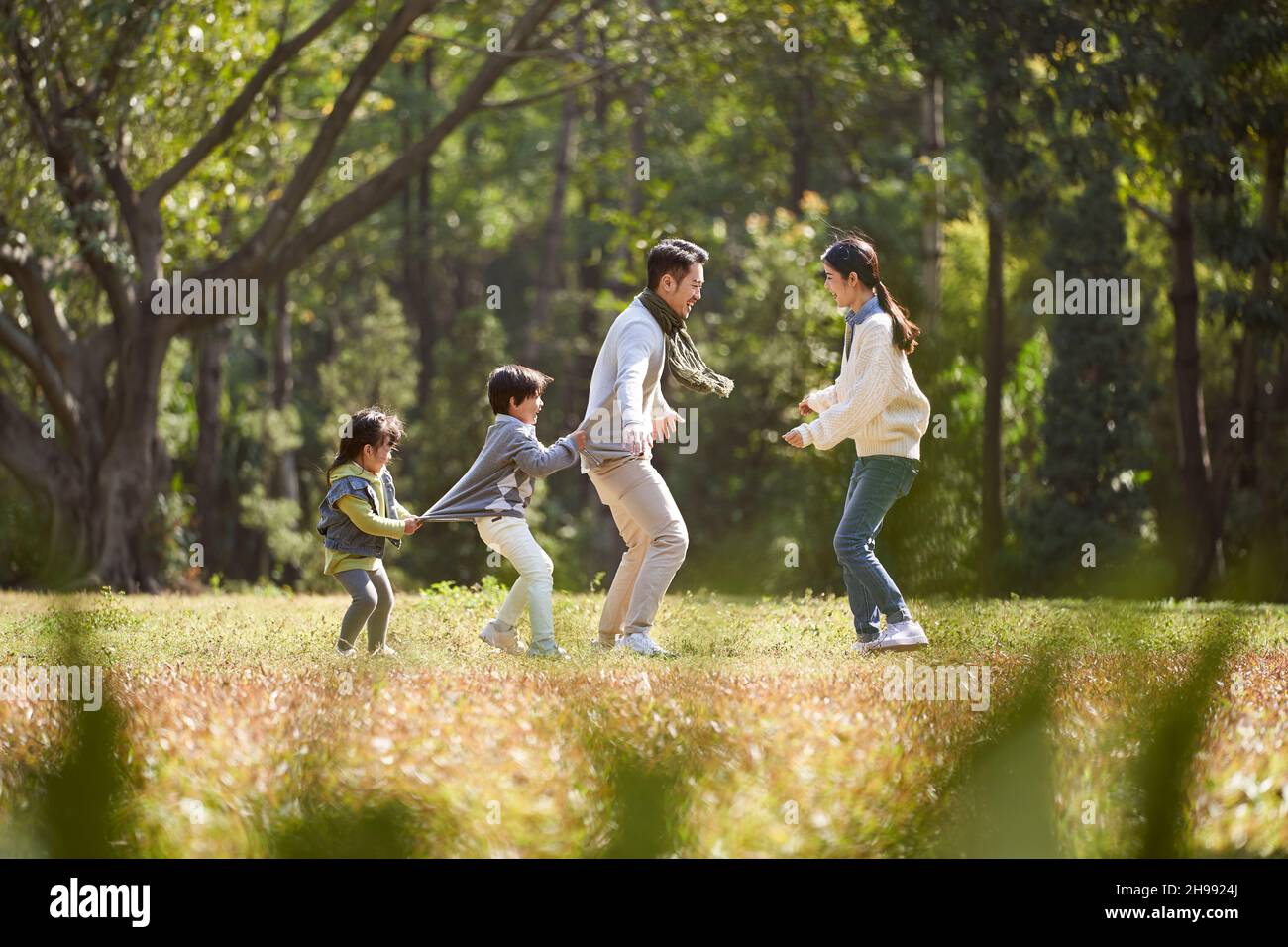 une jeune famille asiatique avec deux enfants qui s'amusent à jouer à l'extérieur dans le parc Banque D'Images