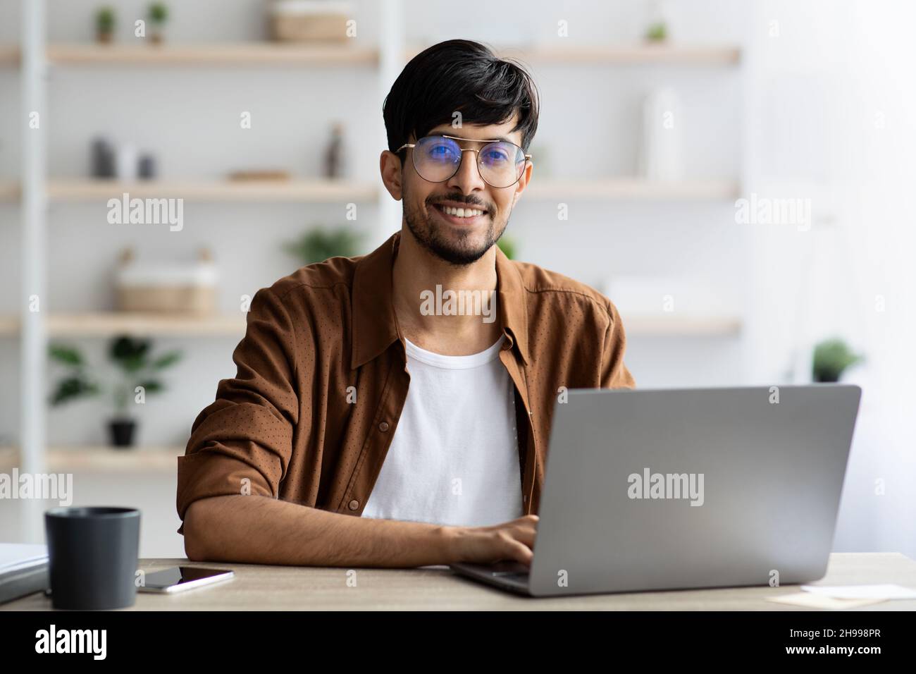 Portrait d'un homme indien joyeux travaillant sur un ordinateur portable Banque D'Images