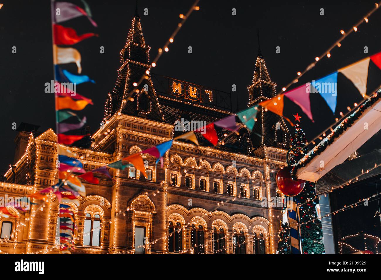 Bâtiment doré avec lumières magiques du soir décorées de guirlandes et drapeaux festifs.Nouvel an et atmosphère de Noël à Moscou Banque D'Images