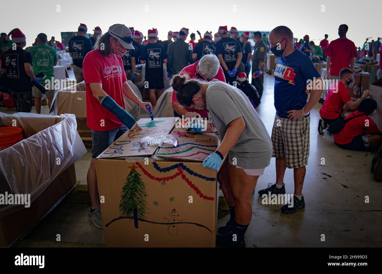 Yigo, États-Unis.04e décembre 2021.Les bénévoles emballez les produits donnés et décorent les paquets de gouttes d'air avec des messages à l'appui de la 70e chute de Noël annuelle de l'opération à la base aérienne d'Andersen le 4 décembre 2021 à Yigo, Guam.Chaque mois de décembre, des équipages feront don par avion de nourriture, de fournitures, de matériel éducatif et d’outils à 55 nations insulaires du Pacifique Sud-est.Crédit: 1lt.Jade Watkins/US Airforce photo/Alamy Live News Banque D'Images