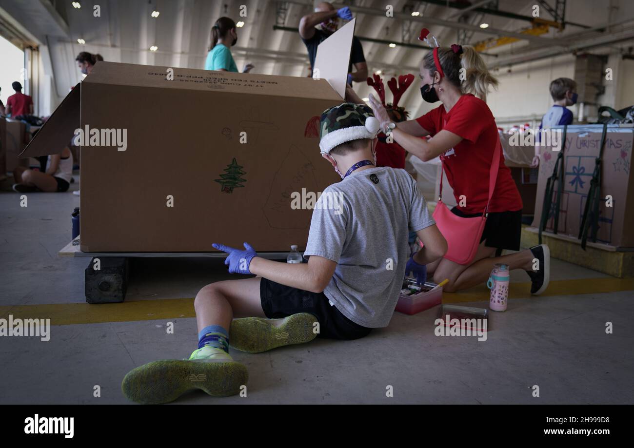 Yigo, États-Unis.04e décembre 2021.Les bénévoles emballez les produits donnés et décorent les paquets de gouttes d'air avec des messages à l'appui de la 70e chute de Noël annuelle de l'opération à la base aérienne d'Andersen le 4 décembre 2021 à Yigo, Guam.Chaque mois de décembre, des équipages feront don par avion de nourriture, de fournitures, de matériel éducatif et d’outils à 55 nations insulaires du Pacifique Sud-est.Crédit: 1lt.Jade Watkins/US Airforce photo/Alamy Live News Banque D'Images