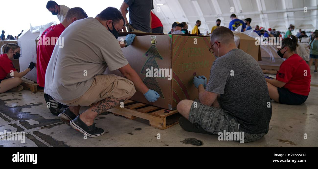 Yigo, États-Unis.04e décembre 2021.Les bénévoles emballez les produits donnés et décorent les paquets de gouttes d'air avec des messages à l'appui de la 70e chute de Noël annuelle de l'opération à la base aérienne d'Andersen le 4 décembre 2021 à Yigo, Guam.Chaque mois de décembre, des équipages feront don par avion de nourriture, de fournitures, de matériel éducatif et d’outils à 55 nations insulaires du Pacifique Sud-est.Crédit: 1lt.Jade Watkins/US Airforce photo/Alamy Live News Banque D'Images