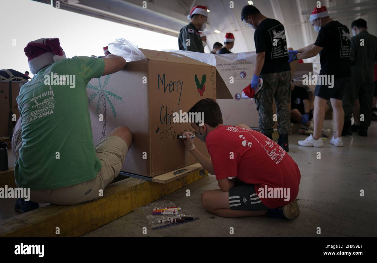 Yigo, États-Unis.04e décembre 2021.Les bénévoles emballez les produits donnés et décorent les paquets de gouttes d'air avec des messages à l'appui de la 70e chute de Noël annuelle de l'opération à la base aérienne d'Andersen le 4 décembre 2021 à Yigo, Guam.Chaque mois de décembre, des équipages feront don par avion de nourriture, de fournitures, de matériel éducatif et d’outils à 55 nations insulaires du Pacifique Sud-est.Crédit: 1lt.Jade Watkins/US Airforce photo/Alamy Live News Banque D'Images