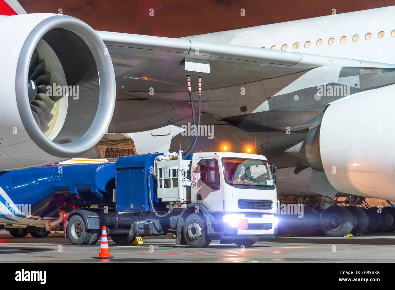 Camion avec un réservoir de kérosène de carburant d'aviation relié aux réservoirs de carburant d'un avion de grande taille, service de ravitaillement d'un vol de nuit Banque D'Images