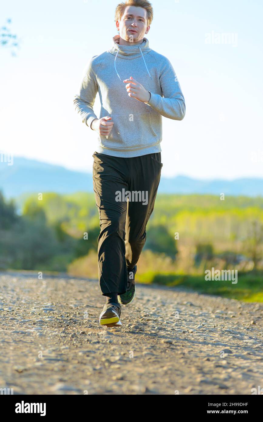 Homme courant jogging dans la nature rurale à la belle journée d'été. Modèle de fitness sportif entraînement ethnique caucasien en extérieur. Banque D'Images