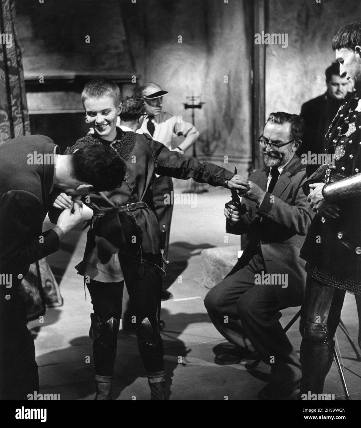 JEAN SEBERG sur le plateau Candid aux Shepperton Studios avec le cinéaste GEORGES PERINAL en arrière-plan et le concepteur de production ROGER FURSE(ajustement de son costume)Pendant le tournage de SAINT JOAN 1957 réalisateur / producteur OTTO PREMINGER basé sur le scénario de George Bernard ShawGraham Greene costume design John McCorry US - UK co-production Wheel Productions / United Artists Banque D'Images