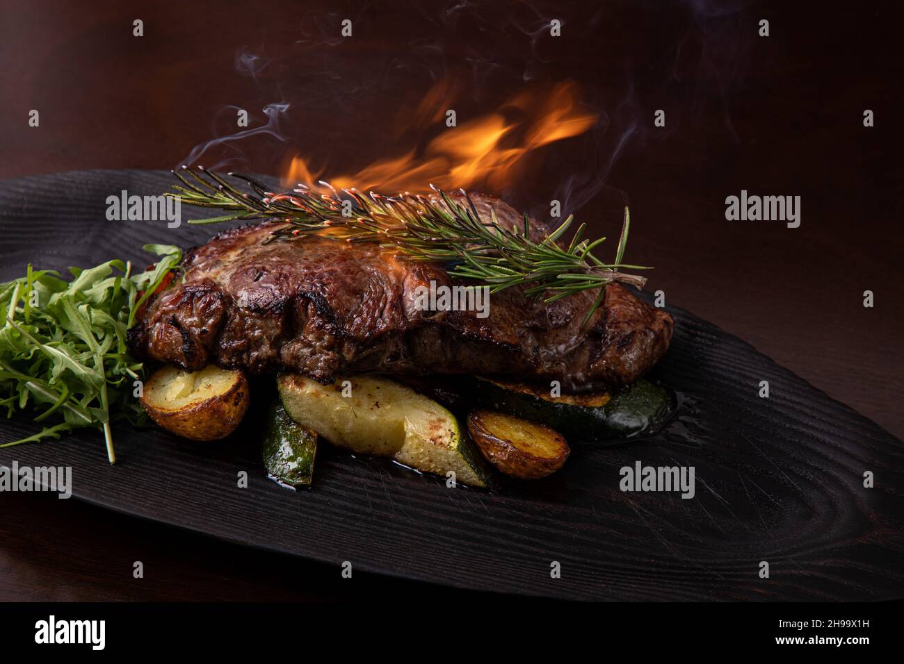 Steak de stripine grillé sur un plat noir. Avec pommes de terre frites et légumes Banque D'Images