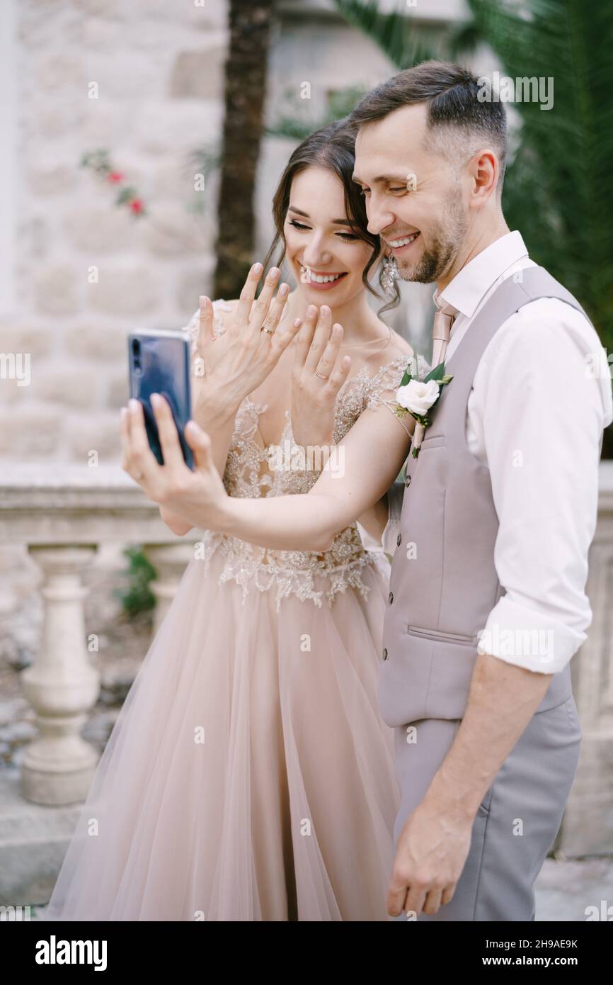 Mariée et marié prendre un selfie avec des anneaux sur leurs doigts sur un smartphone Banque D'Images