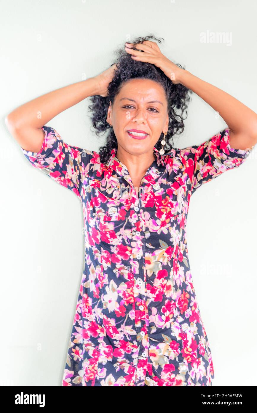 Portrait d'une femme portant une robe colorée sur fond gris clair.Salvador, Bahia, Brésil. Banque D'Images