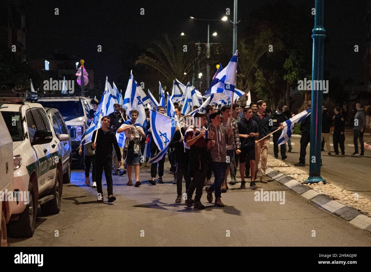 Chef d'équipe en service, Israël.5 décembre 2021, l'aile droite religieuse israélienne marche en public avec des drapeaux à travers la ville mixte de Lod, célébrant la dernière bougie de la fête de Hanoukkah.L'événement a été organisé par des groupes sionistes religieux, certains d'entre eux percived comme radicaux en Israël, visant à étendre le présent juif dans le pays.La ville de Lod est peuplée à la fois de juifs et de musulmans, qui vivaient en paix jusqu’à l’arrivée d’un « noyau de la Torah » dans la ville.Credit: Matan Golan/Alay Live News Banque D'Images