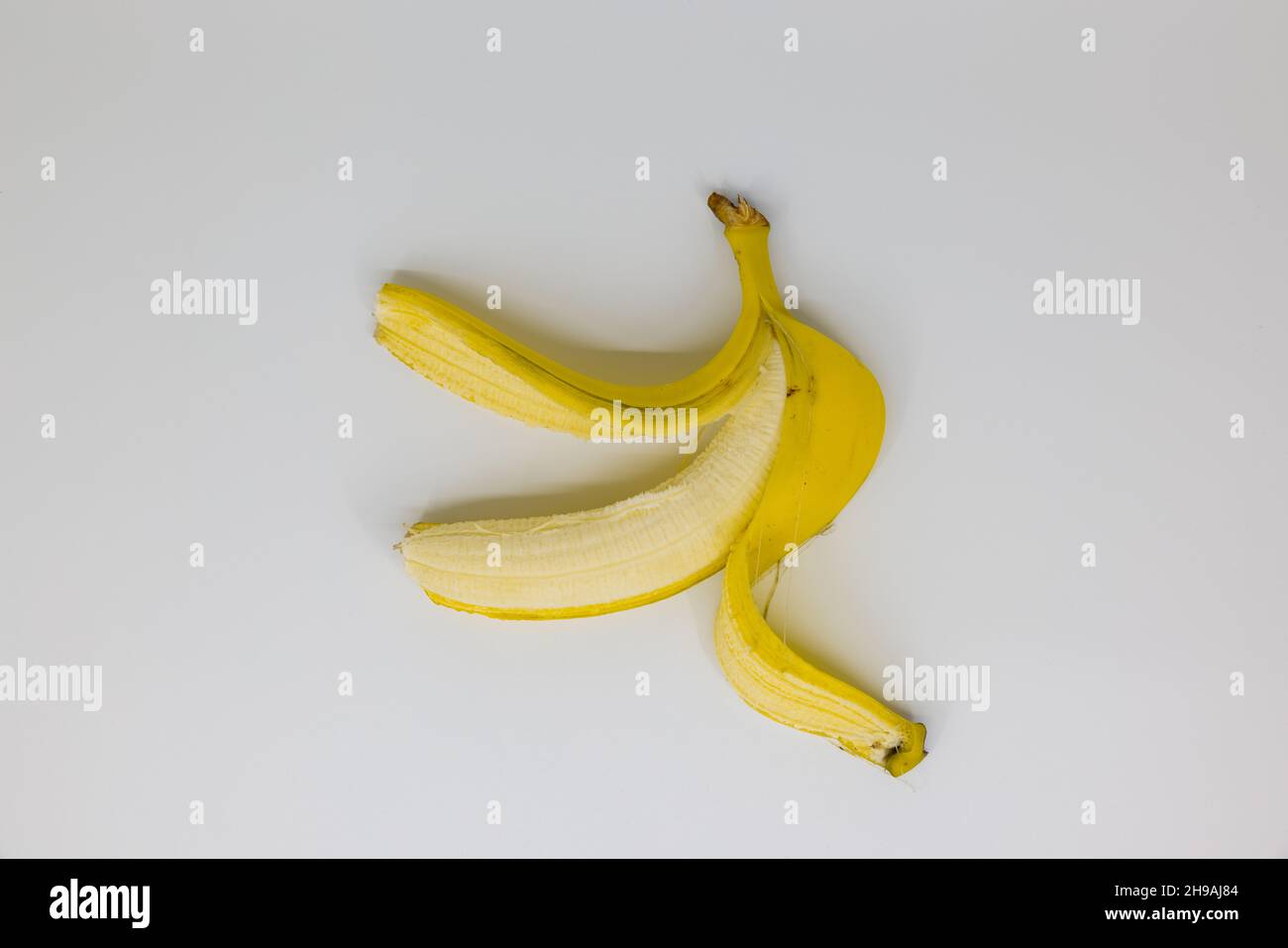 banane jaune pelée simple sur fond blanc, grenaille en studio, les fruits sont sains Banque D'Images