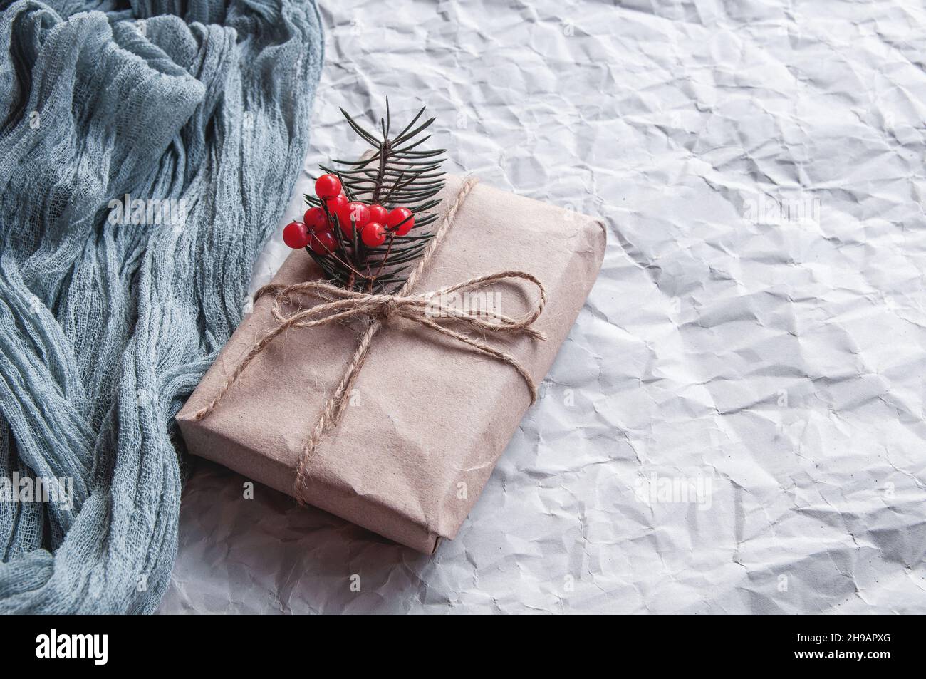 Boîte cadeau en papier style vintage Craft avec fond bleu de nappe de Gauze.Branches de sapin et baies rouges comme décoration sur fond gris Banque D'Images