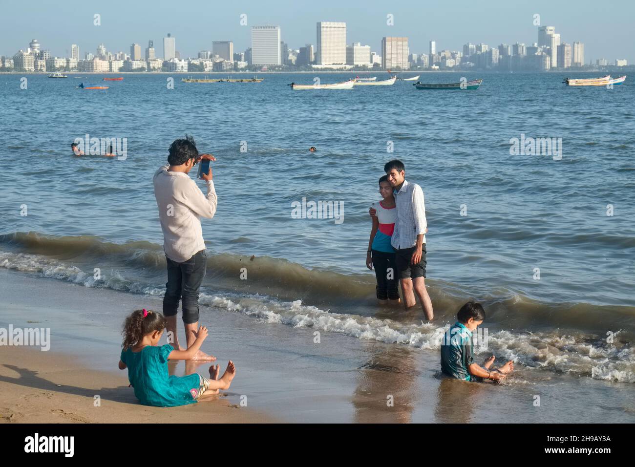 Des millénaires à Chowpatty Beach à Mumbai, en Inde, prenant des photos sur un mobile, la ligne d'horizon de Marine Drive et au-delà en arrière-plan Banque D'Images