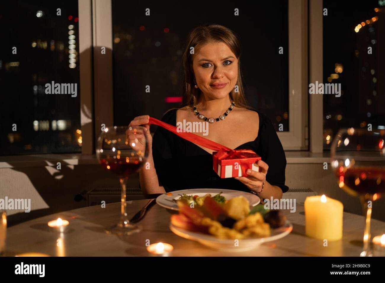 30s fille avec cadeau pour la saint valentin, dîner aux chandelles femme attendant son mari, rendez-vous dans un restaurant le soir Banque D'Images