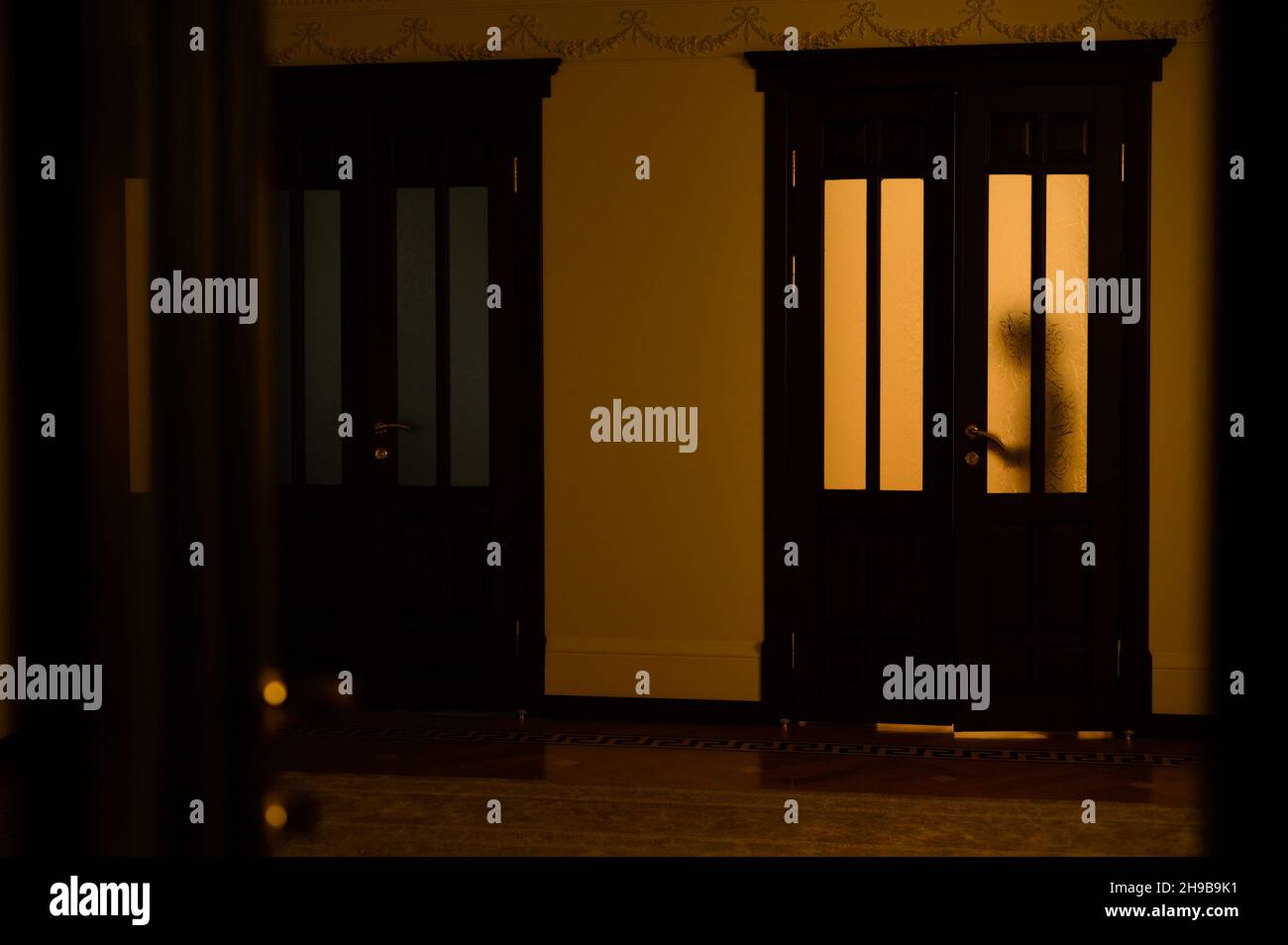 silhouette d'enfant dans la fenêtre de porte éclairée par une lumière chaude au coucher du soleil à l'intérieur de la maison Banque D'Images