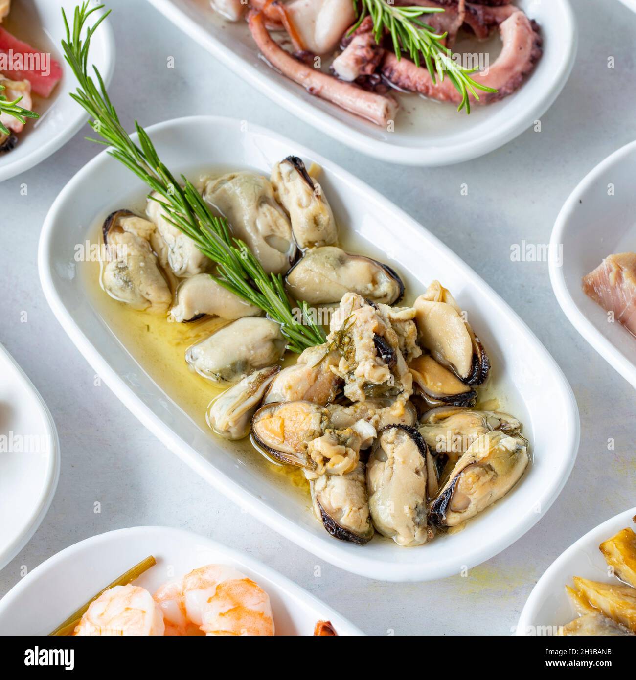 Ensemble de plats de fruits de mer.Fruits de mer sur une assiette.Sur fond blanc en bois.Moules marinées à concentration sélective.Crevettes, lakerda, salade de poulpes, moules Banque D'Images