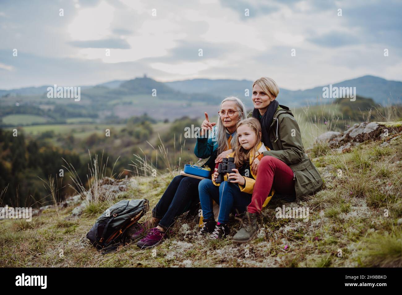 Petite fille avec mère et grand-mère assis et lookiong à la vue sur le sommet de la montagne. Banque D'Images