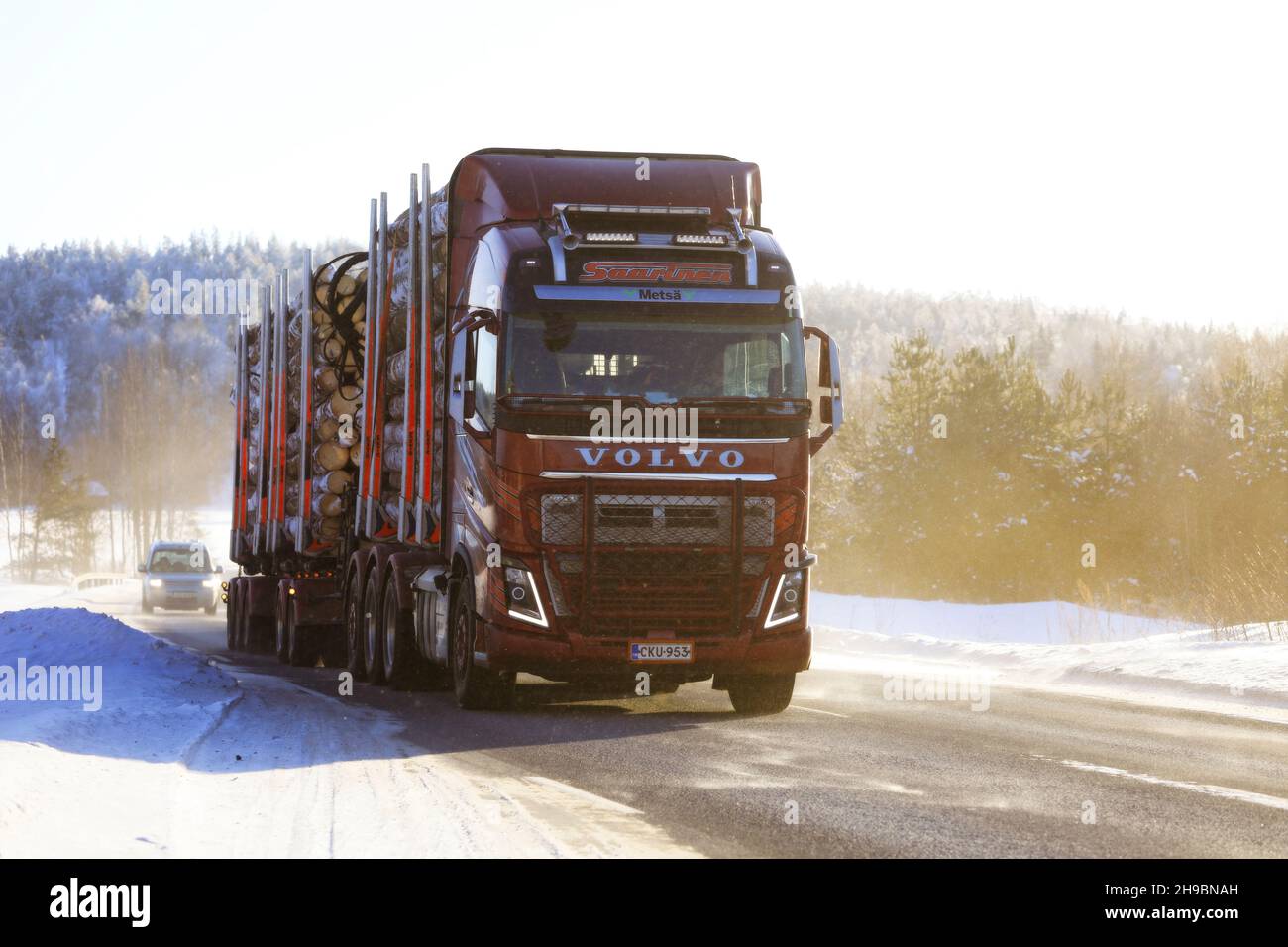 Le camion routier Red Volvo FH16 750 de Kuljetusliike Seppo Saarinen transporte une charge sur route sous la lumière du soleil et la poussière de neige en hiver.Salo, Finlande.11 février 2021 Banque D'Images