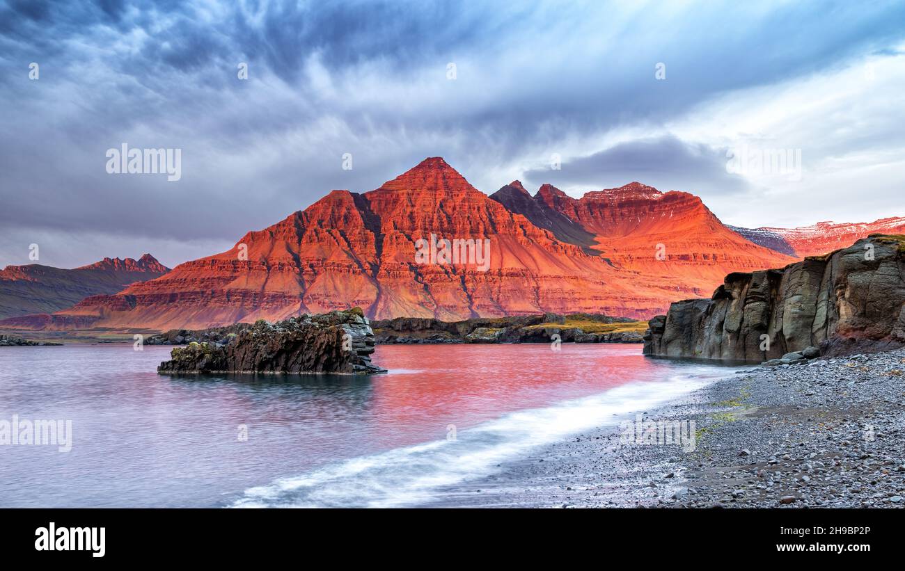 La Bulandstidur, ou montagne Pyramide, dans la région du fjord oriental de l'Islande.Pendant quelques instants, le rocher brille de rouge lorsque le soleil se lève. Banque D'Images
