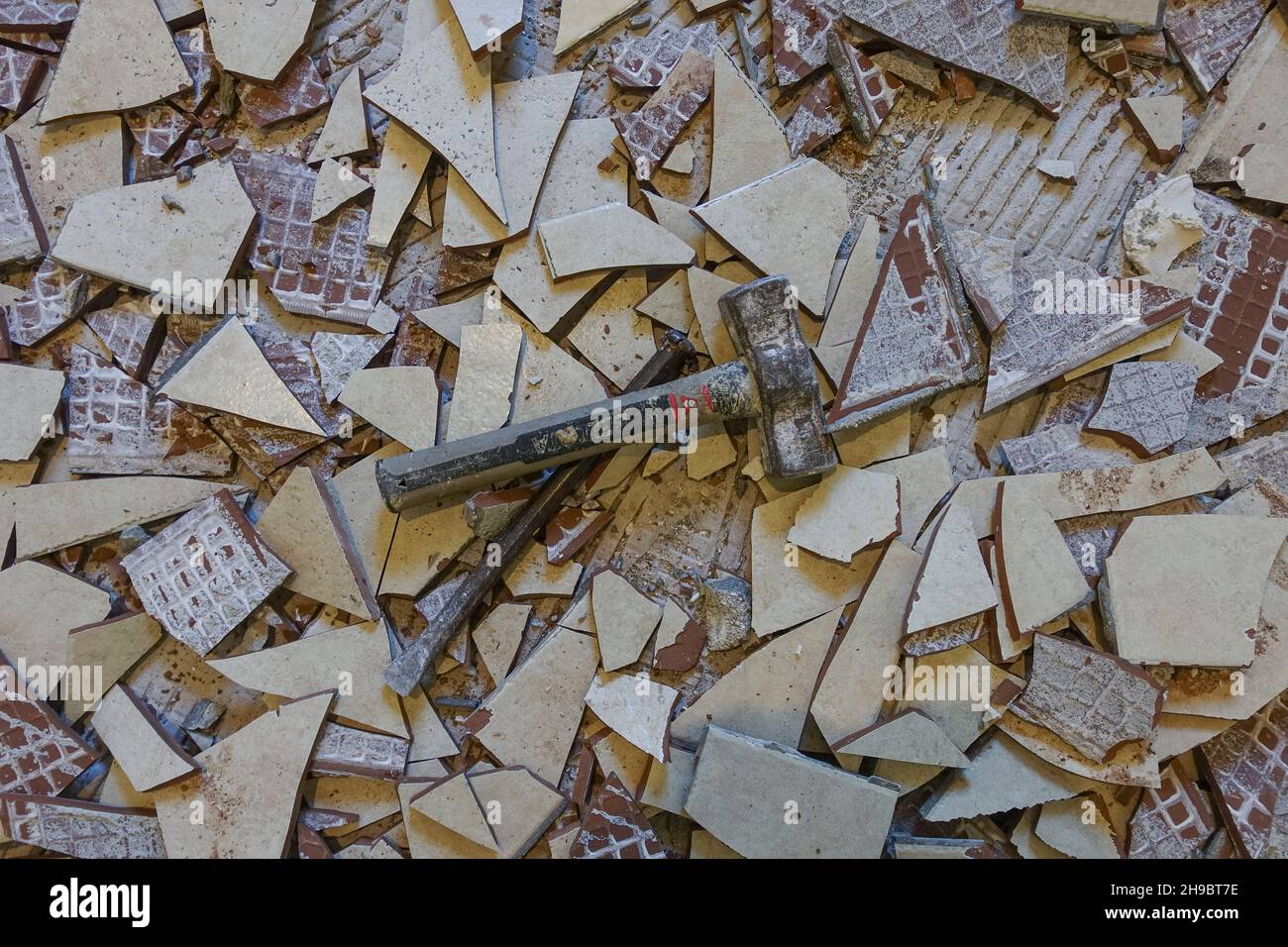 Un plancher de cuisine recouvert de carreaux de plancher cassés, un marteau et un burin. Banque D'Images