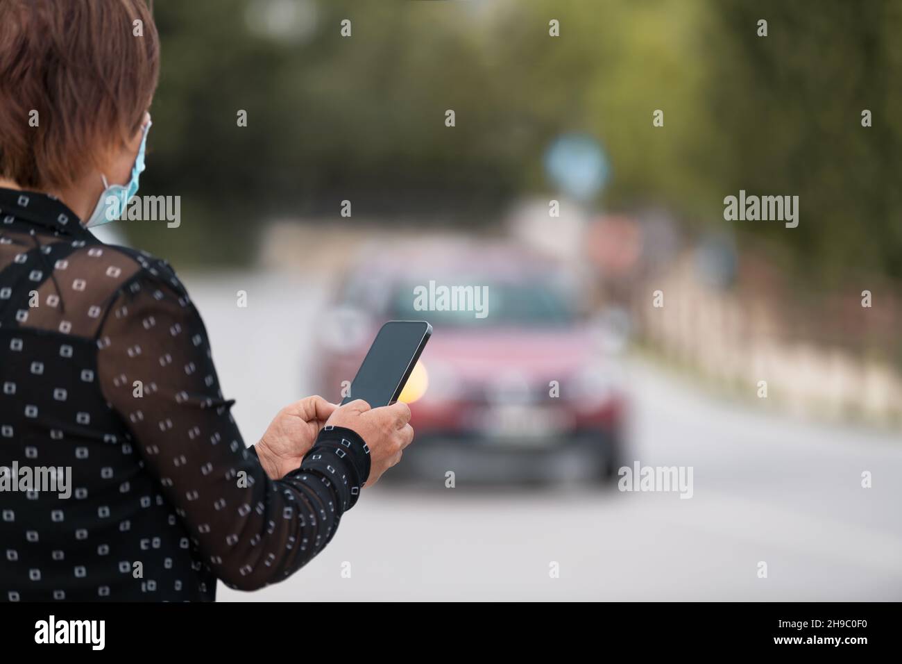 Femme tenant un smartphone entre les mains et envoyant des messages en ligne dans la rue.Vue arrière Banque D'Images