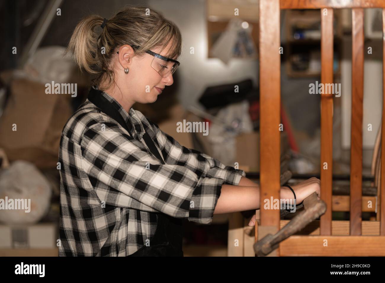Une jeune femme répare une chaise en bois Banque D'Images