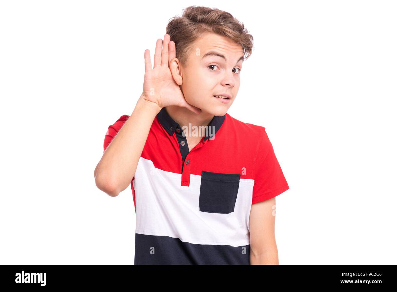 Garçon adolescent avec la main sur l'oreille écoutant une audition pour ragots.Gros plan portrait l'adolescent tient sa main près de l'oreille et écoute attentivement, isolé sur blanc Banque D'Images