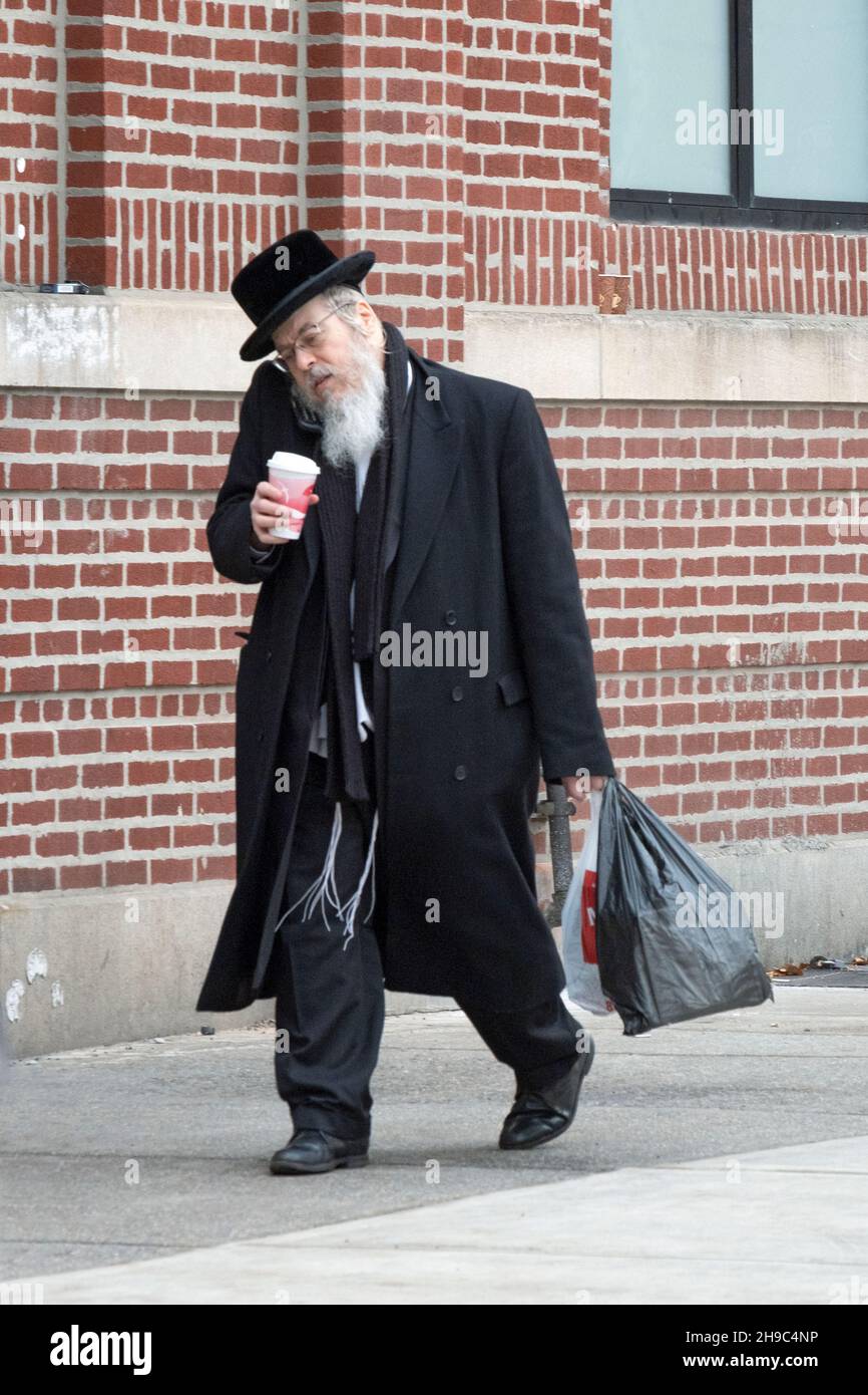 MULTITÂCHE.Un orthodoxjuif marche, parle au téléphone, porte un sac et boit du café.À Williamsburg, Brooklyn, New York. Banque D'Images